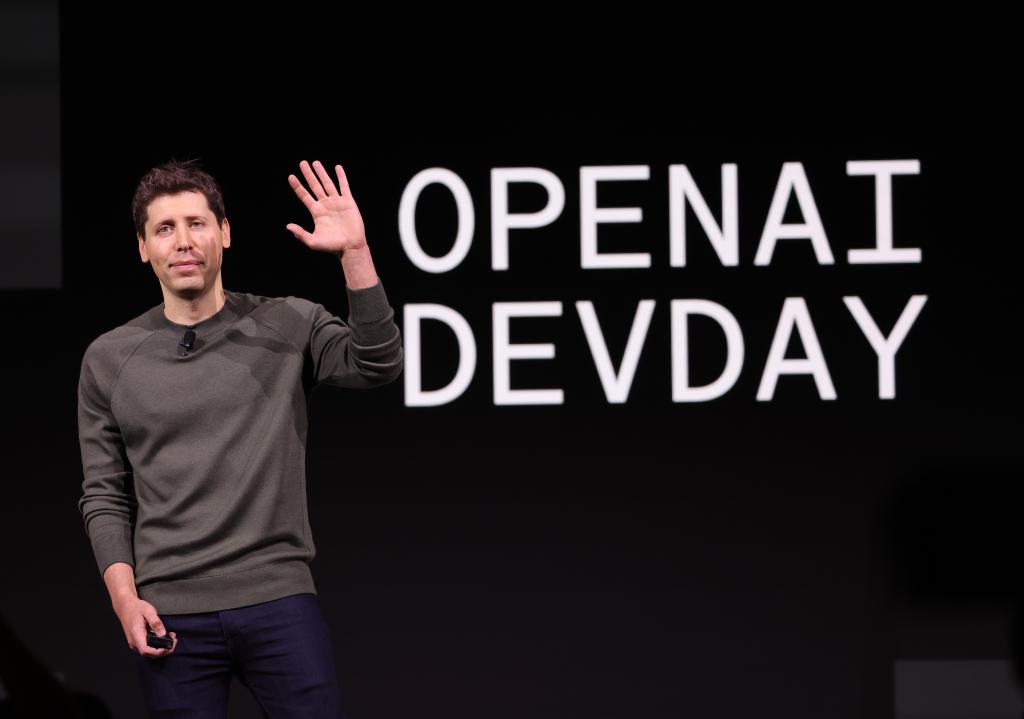 Sam Altman waving at a crowd during an OpenAI Dev Day